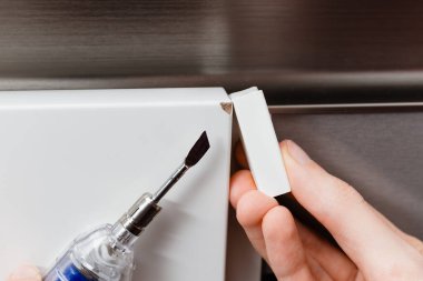 Isıtma spatulası ve beyaz balmumu çubuğunu kırık bir köşeyi onarmak için kullanan bir insan. mobilya tamiri, yüzey restorasyonu