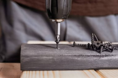 Elektrikli tornavidayla oynayan tamirci. Siyah vida. Tahta, marangozluk, DIY onarımı.