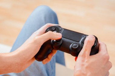 Eller, parmakları tuşlara ve joystick 'e basan siyah bir video oyunu denetleyicisini kavrıyor.