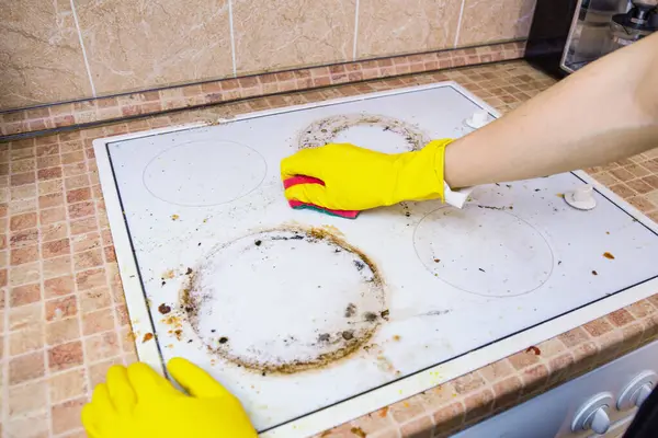 Sarı eldivenli eller kir temizler veya beyaz elektrikli ocaktan çıkan yağlar fayanslı mutfak tezgahında sünger kullanırlar, ev temizliği, hijyen...