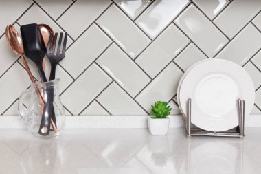 Cam sürahide mutfak gereçleri ve bulaşık rafında beyaz tabaklar temiz tezgahta dinleniyor ve parlak fayanslı arka plan, ev dekorasyonu, mutfak tasarımı