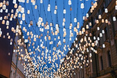 Parlayan fenerlerin çoğu klasik binaları olan bir şehir caddesinin üzerinde alacakaranlıkta, şenlikli aydınlatmada, kamu dekorasyonunda asılı duruyor.