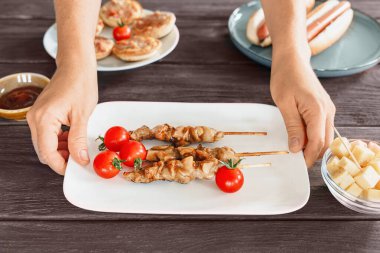 Beyaz bir tabakta ızgara yakitori tavuk şişi. Kırsal bar masasında atıştırmalık olarak servis ediliyor. Bira aperatifi.