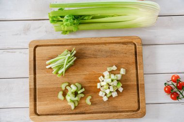 Kereviz sapları ahşap bir tahtanın üzerinde birçok şekilde dilimlenmiş, üst manzara, yemek hazırlığı için. Sağlıklı yemek.