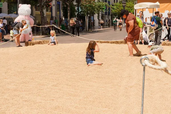 Valencia 'daki Fiesta del Arroz' da çıplak ayaklı çocuklar pirinç içinde emeklerken aileler ve turistler İspanya 'yı, Valencia' yı, 05.06.2023 'ü izliyor.
