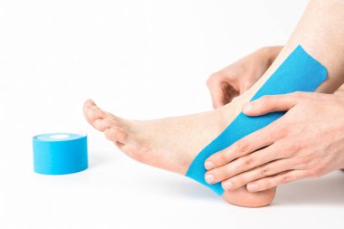 Lastik kineziyoloji bandı kasları desteklemek, gerilimi azaltmak ve iyileşmeye yardımcı olmak için ayak ve ayak bileğinin üst kısmına uygulanır..