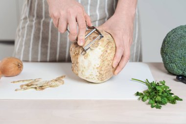 Eller kereviz kökünden kabuk soymak ya da çıkarmak için metal sopa kullanır. Pişirme hazırlığı, kök sebze.