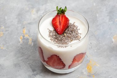 Kremalı süt ürünleri katmanlı tatlı üzerine taze çilek ve chia tohumları, kahvaltı fikri, süt ürünleri atıştırmalığı.