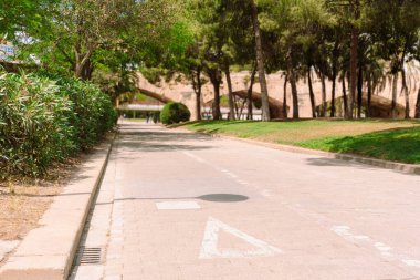 Boş bisiklet, Valencia 'daki Turia Bahçeleri' nden geçiyor. Ağaçlar, çalılar ve eski bir taş köprü, şehir yeşilliği ve bisiklet ile çevrili.