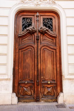 Aslan başlı simetrik oyma ahşap kapı, çiçek demiri kafes, ve tarihi İspanyol binasında eğri çerçeve, mimari cephe, dekoratif ahşap