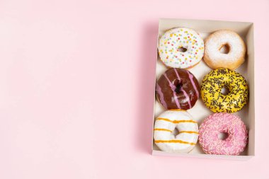 Süslü, şekerli ve pudra şekerli altı çöreğin en üst görüntüsü pembe bir arka planda paket, fırın paketi, kopyalama alanı.