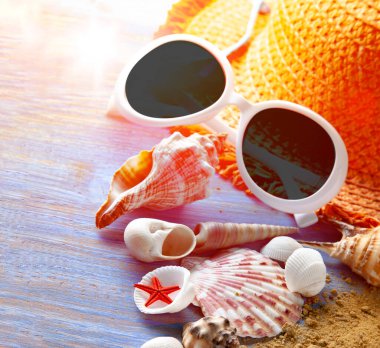 Plaj aksesuarları, gözlük, tahta güverte kumlarında midye kabukları.