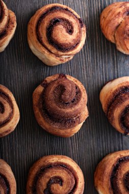 Taze pişmiş tarçınlı çörekler ve ahşap arka planda baharatlar. Noel pastaları. Yakın plan. Üst görünüm.