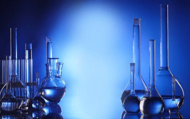 Retort, matara, damlatıcı, laboratuvar tüpü cam masada mavi arka planda mavi sıvıyla. Laboratuvar analizi