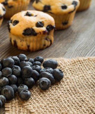 Ahşap bir masada yaban mersinli kek. Tahtada taze böğürtlen ve tatlı hamur işleri