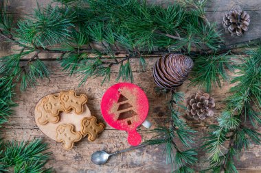 Noel kurabiyeleri, üst manzara nefis zencefilli kurabiye ya da Noel ya da yeni yıl için çam ağacı dallarıyla süslenmiş ahşap masadaki bisküviler. Adam şeklinde noel bisküvileri ve masada bir fincan kahve.