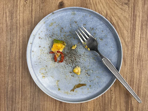 木製のテーブルの上のプレート上の朝食のオムレツの残り物 テーブルの上の青い皿に残り物 朝食や健康食品のコンセプト写真を木の背景に — ストック写真