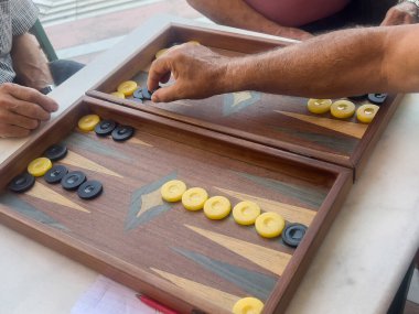 Backgammon, closeup hands of man playing greek style backgammon in Greece. playing board games. leisure activities with friends clipart