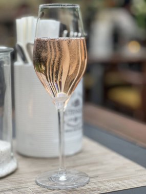 Şampanya, yan gözle gül şarabı ya da masada seçici odak noktası fotokopi alanı olan bulanık bir restoran. Kutlama konsepti. Bir bardak Prosecco veya gül şarabı. içki arkaplanı