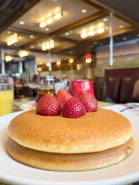 pancakes, side view delicious and beautiful pancakes with strawberry on table over blurred cafe or restaurant. sweet food for breakfast in American culture. dessert with strawberry fruit on table