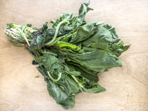 rotten, top view bunch of rotten mould arugula salad leaves on wooden background or surface. healthy raw food in bad condition. expired food ingredient