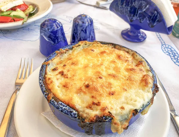 greek food, delicious traditional moussaka with bechamel sauce cooked in a casserole on table in Greece. typical greek moussaka made from aubergine. local food concept.