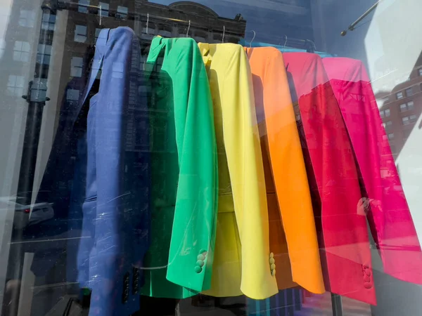lgbt pride, colorful clothes and jackets on hangers in window display of a store or boutique for lgbt pride day. shopping concept. shop display window with colorful clothes