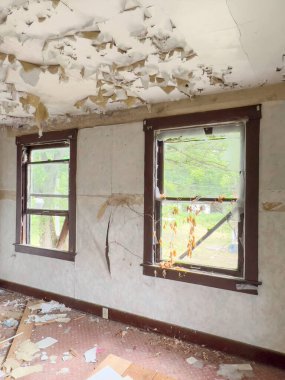 Terk edilmiş, terk edilmiş, tavanı soyulmuş ve kirli zemini olan bir evin içi. Eski harabe ev içi. Hasarlı duvarlar ve yıkılmış bir binanın kırık camları. Yoksulluk. savaş konsepti