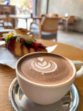 Kahve, yan manzara nefis ve bir fincan kapuçino kahve, kahve ve bir kafedeki ayçöreği üzerine seçici bir odaklanma. Masada kapuçino bardağı ve kruvasanla kahvaltı..