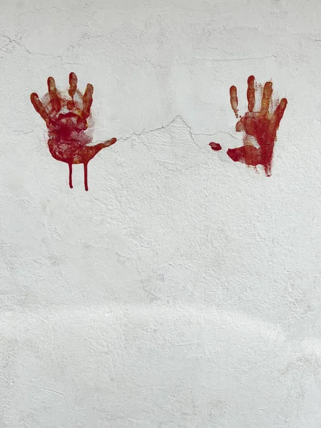 handprints, horror or Halloween background or surface with bloody red hands print on white wall with copy space. halloween background with hand shaped red stamps on white wall with copy space