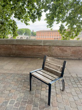 Avrupa 'da gölgeler oluşturan ağaçların altındaki parktaki ahşap bankta. Avrupa 'da nehir kenarına. Baharda ya da yaz aylarında ağaç yapraklarının altında dinlenmek ve serinlemek için ahşap bir bank koltuğu.. 