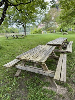 Piknik, yan görüş boş ahşap piknik masası yeşil çimlerin üzerinde parkın güneşli bir gününde bahar ya da yaz aylarında. Kamp konsepti ya da yüzey. Ormanda ya da parkta boş ya da boş bir tahta masa. bahar