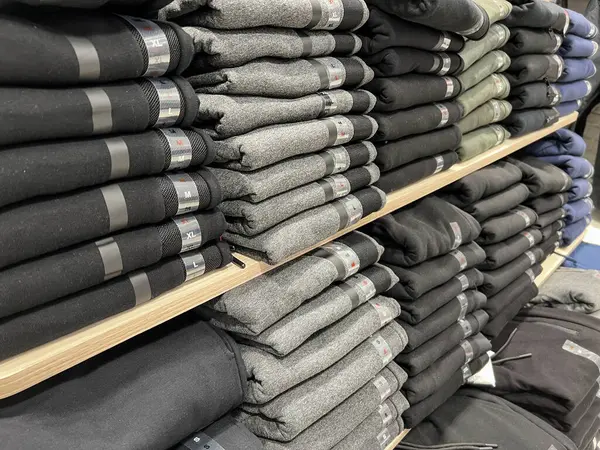 shopping, Stack of folded clothes for sale in store. row of new menswear clothes or casual trousers on shelves in department store. shopping concept background or surface
