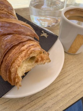 Kruvasan, yakın plan kahve, sabah için gevrek Fransız kruvasanı. Fransa 'da geleneksel lezzetli kahvaltı. Fransız yemeği konsepti. Fırın ve kahve. Fransa 'da bir kafe. yendi