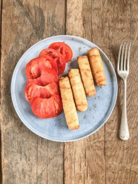 Peynirle doldurulmuş fillo pastasından yapılmış kızarmış börek. Kahvaltıda ya da başlangıç olarak geleneksel Türk yemekleri. Türkiye 'de lezzetli yerel yemekler. Kızarmış fileto ve dilimlenmiş domates.