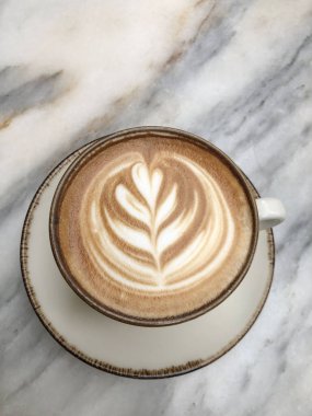 Kahve, bir fincan kapuçino kahve mermer masa üzerinde latte sanat ile ya da Cafe 'de arka plan. Kalpli latte kupası, köpüklü çiçek. Lezzetli latte sanat konsepti. Kafe molası arka planı. İtalyan içeceği
