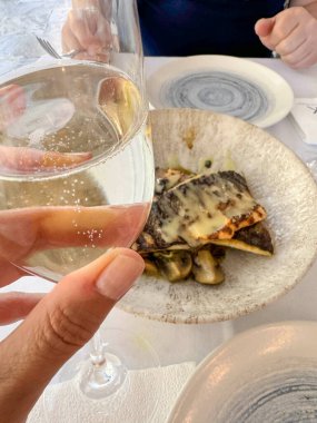 Şarap, kadın eli Prosecco 'yu tutar ya da lezzetli deniz ürünleriyle dolu hareketli bir yemek ortamında köpüklü şarap kadehi. Bir İtalyan lokantasında kutlama ve neşe anları yakalıyorum. Şampanya, deniz ürünleri.