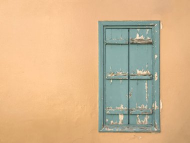 Pencere, kapalı yıpranmış turkuaz ahşap kepenk ve duvarda fotokopi alanı olan boyalar. Kırsal pencere perdeleri, Akdeniz arka planı. Pastel şeftali rengi yüzeyi