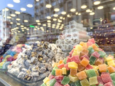 Turkish delight assortment in shop window, colorful cubes, nut filled, coconut coated varieties, traditional Middle Eastern sweets. Confectionery shop window with city reflection in Istanbul, Turkey