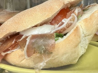 Yemek, yan manzara lezzetli jambonlu jambonlu ve peynirli sandviç kahvaltıda ya da öğle yemeğinde. İtalyan fast food konsepti. Atıştırmalık olarak jambonlu sandviç. Sağlıklı beslenme geçmişi. Atıştırmalık al.