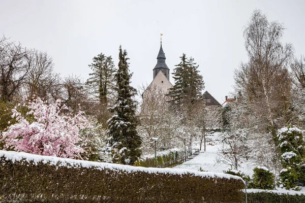 城市的风景与盛开的樱花和覆盖着白雪的树木 一座教堂在远处的山上 — 图库照片