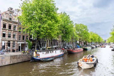 AMSTERDAM, THE NETHERLANDS - August 6, 2022: A large boat with tourists sails on a canal in the city of Amsterdam