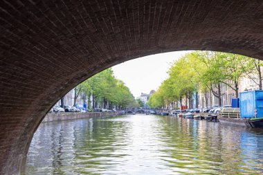 Hollanda, Amsterdam 'da bir köprünün altından bir gemi geçiyor.