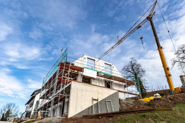 Yerleşim bölgesinde yeni evler inşa ediliyor. İnşaat halindeki bir bina ve gökyüzü arka planında bir vinç.
