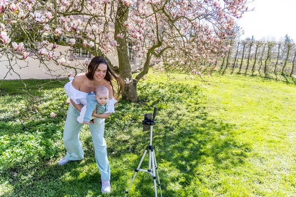 Woman Takes Selfie Baby Her Arms Background Blooming Magnolia — Stock Photo, Image