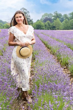 Beyaz elbiseli bir kadın lavanta tarlasında yürüyor.