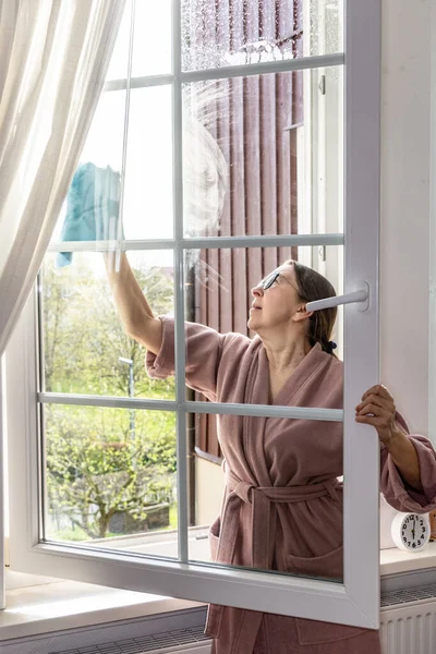 A woman washes a window with a special napkin, home cleaning