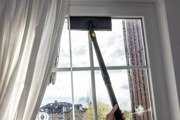 Washing the glass surface of the window with a steam generator brush, cleaning at home