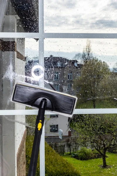 Washing the glass surface of the window with a steam generator brush, cleaning at home
