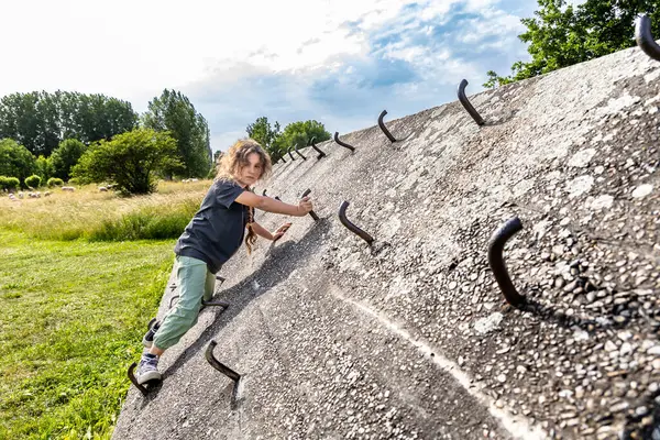 A girl climbs a concrete wall, a climbing wall outdoors